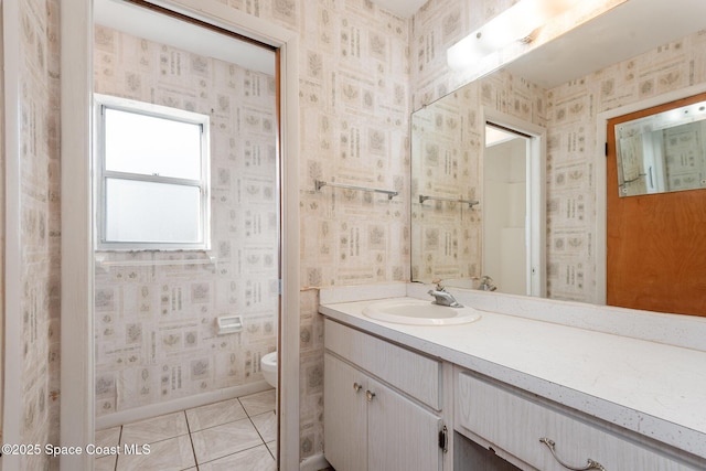 bathroom featuring vanity, baseboards, wallpapered walls, tile patterned flooring, and toilet