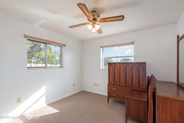 home office with a wealth of natural light, light colored carpet, and a textured ceiling