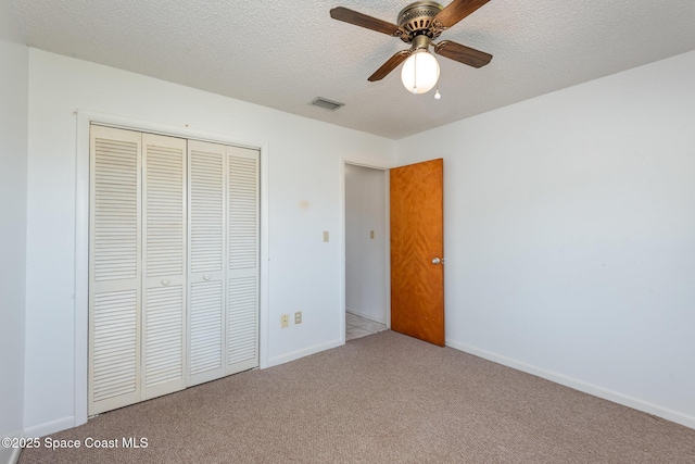 unfurnished bedroom featuring visible vents, a textured ceiling, a closet, carpet, and baseboards