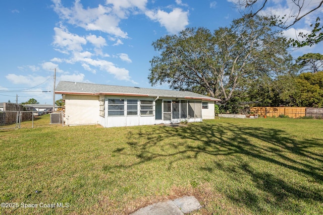 rear view of house featuring a yard, a fenced backyard, and a sunroom