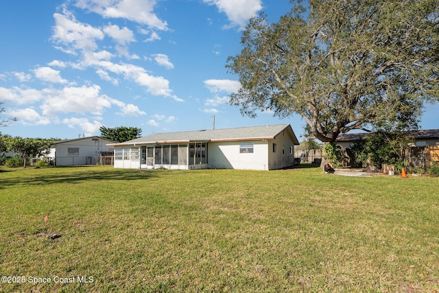 rear view of property featuring fence, a lawn, and a sunroom