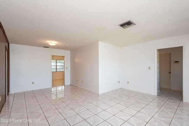 empty room with light tile patterned floors, visible vents, and a textured ceiling