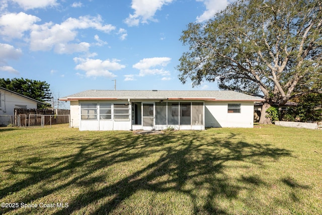 back of house featuring roof with shingles, fence, a yard, and a sunroom