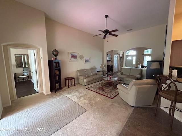 carpeted living area featuring visible vents, a high ceiling, a ceiling fan, and arched walkways