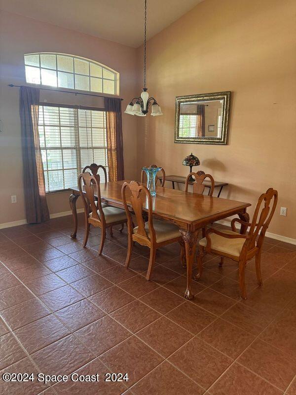 dining area featuring high vaulted ceiling, baseboards, and a chandelier