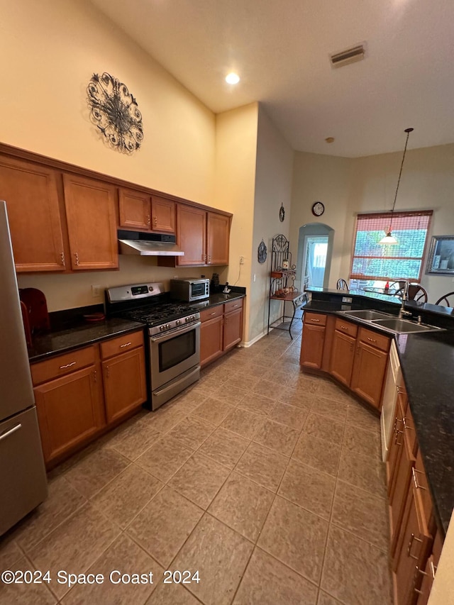 kitchen featuring visible vents, under cabinet range hood, a sink, dark countertops, and stainless steel appliances