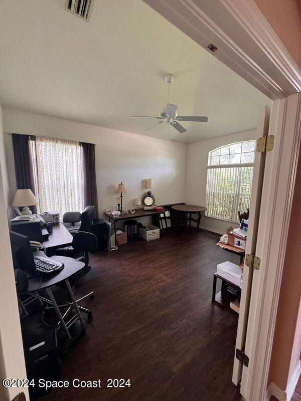 office space featuring a ceiling fan, lofted ceiling, wood finished floors, and visible vents