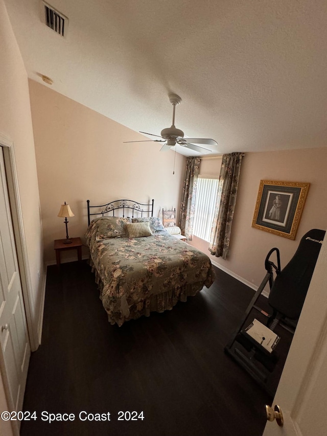 bedroom featuring visible vents, a textured ceiling, wood finished floors, baseboards, and ceiling fan