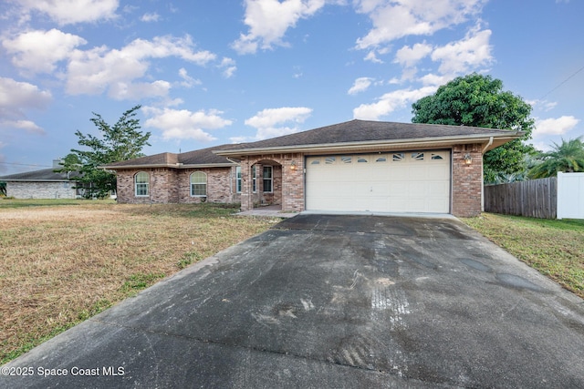 ranch-style house featuring fence, concrete driveway, a front yard, a garage, and brick siding