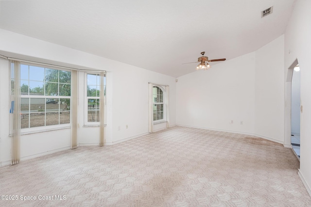 carpeted empty room featuring lofted ceiling, a ceiling fan, visible vents, and baseboards