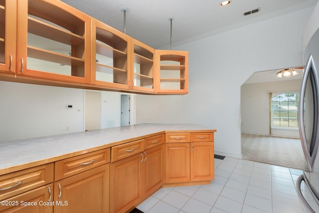 kitchen with glass insert cabinets, light countertops, and freestanding refrigerator