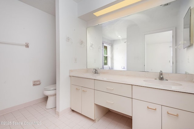 bathroom featuring a sink, baseboards, toilet, and double vanity