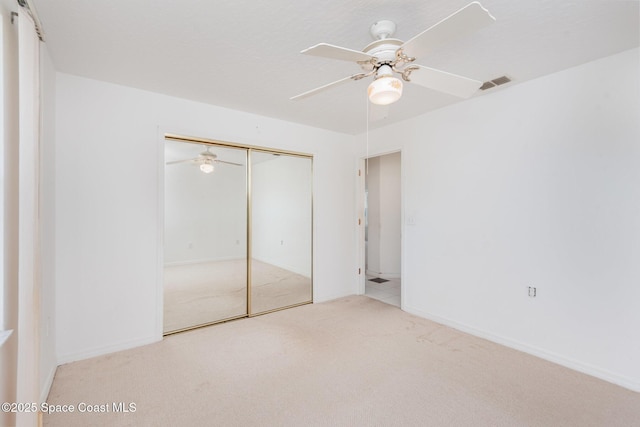 unfurnished bedroom featuring baseboards, visible vents, carpet floors, ceiling fan, and a closet