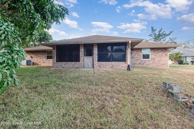 rear view of property featuring a lawn and brick siding