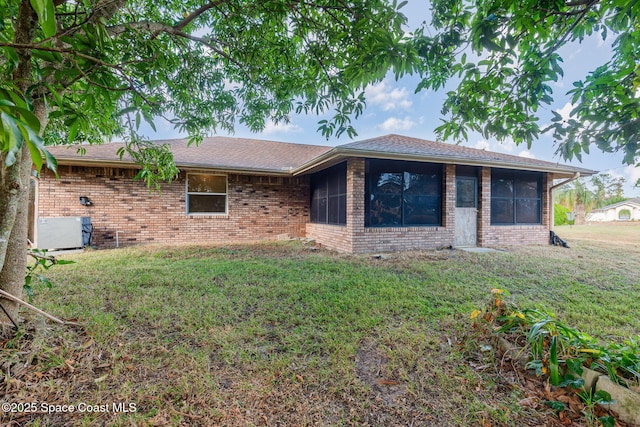 ranch-style house with cooling unit, brick siding, a front lawn, and a sunroom