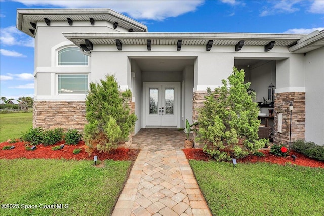 doorway to property with french doors, stone siding, a lawn, and stucco siding