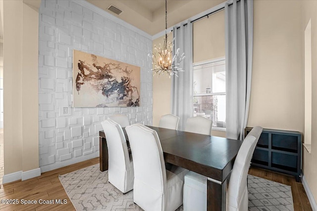 dining room with baseboards, wood finished floors, visible vents, and a chandelier