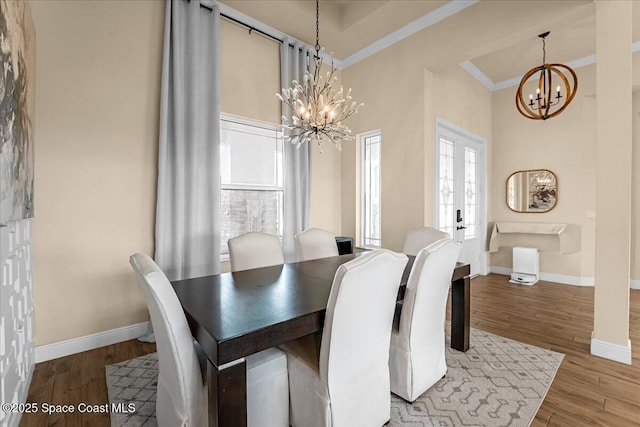 dining room with a chandelier, ornamental molding, baseboards, and wood finished floors