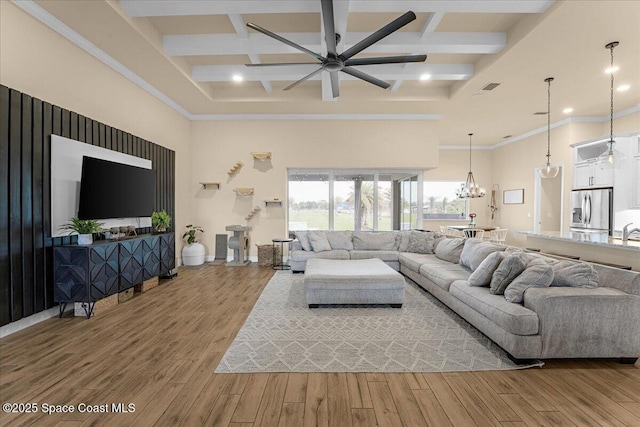 living area featuring ceiling fan with notable chandelier, coffered ceiling, a high ceiling, and wood finished floors