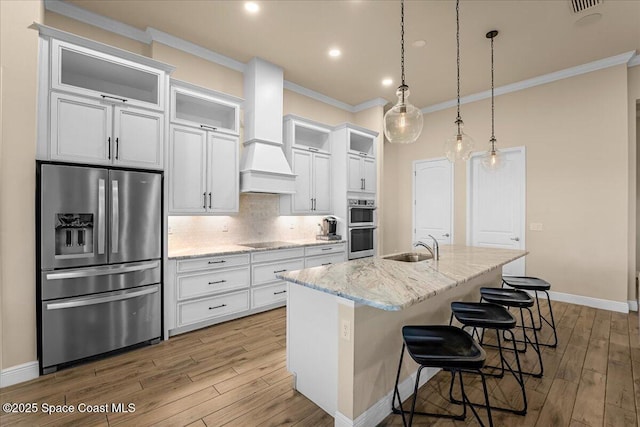 kitchen with custom exhaust hood, a sink, decorative backsplash, appliances with stainless steel finishes, and crown molding