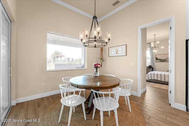 dining area with light wood-type flooring, visible vents, a chandelier, and ornamental molding