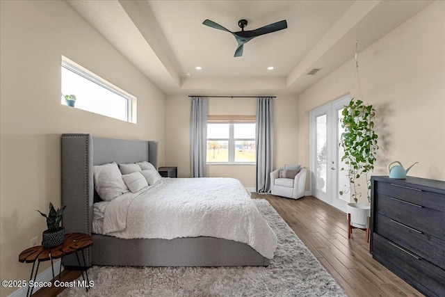 bedroom with visible vents, a tray ceiling, recessed lighting, wood finished floors, and access to outside