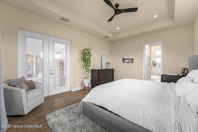 bedroom with visible vents, dark wood finished floors, multiple windows, french doors, and a raised ceiling