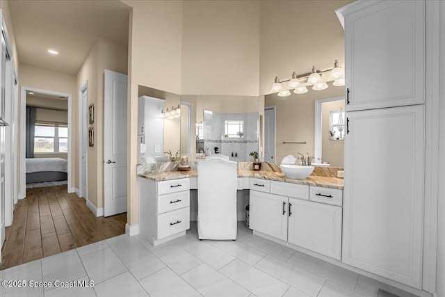 ensuite bathroom with tile patterned floors, ensuite bath, a high ceiling, baseboards, and vanity