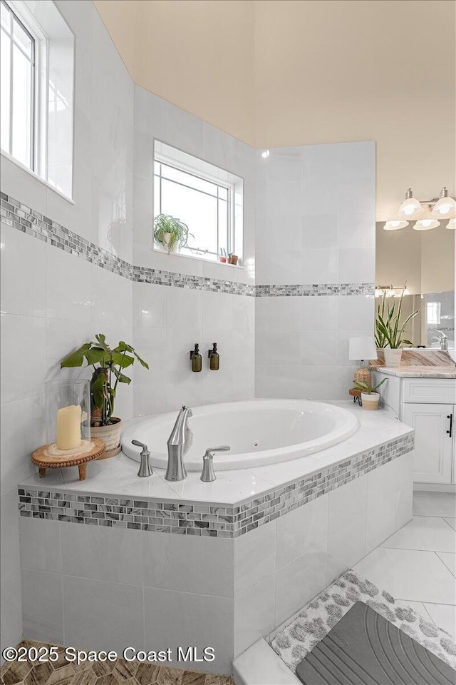 full bathroom featuring vanity, tile patterned floors, a jetted tub, and tile walls