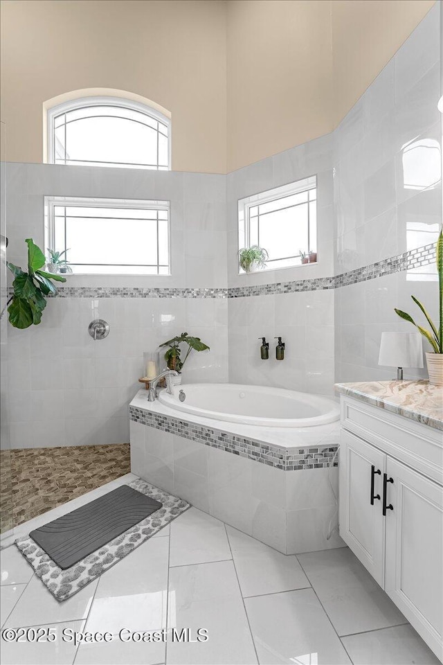 full bathroom with vanity, tiled shower, a garden tub, tile walls, and tile patterned floors