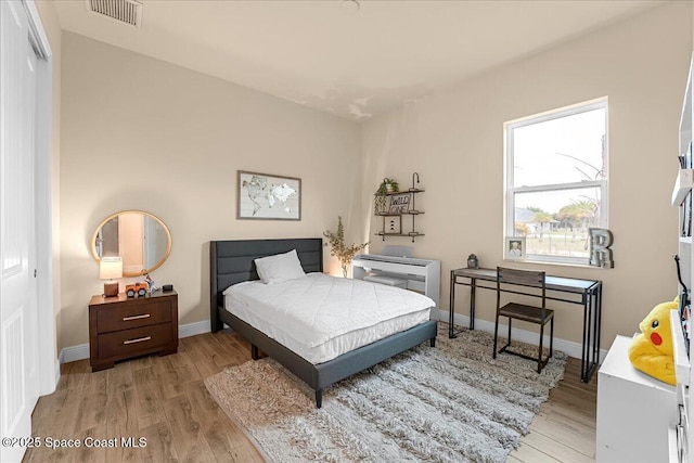 bedroom with light wood-style floors, visible vents, a closet, and baseboards