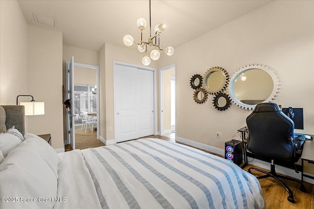 bedroom with connected bathroom, wood finished floors, baseboards, and a chandelier