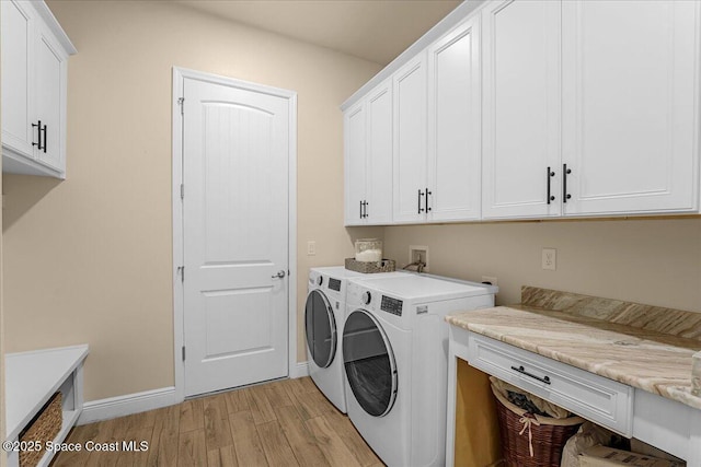 clothes washing area featuring washer and dryer, cabinet space, baseboards, and light wood finished floors