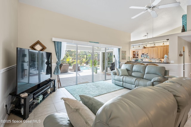 living area featuring light tile patterned floors, high vaulted ceiling, and a ceiling fan