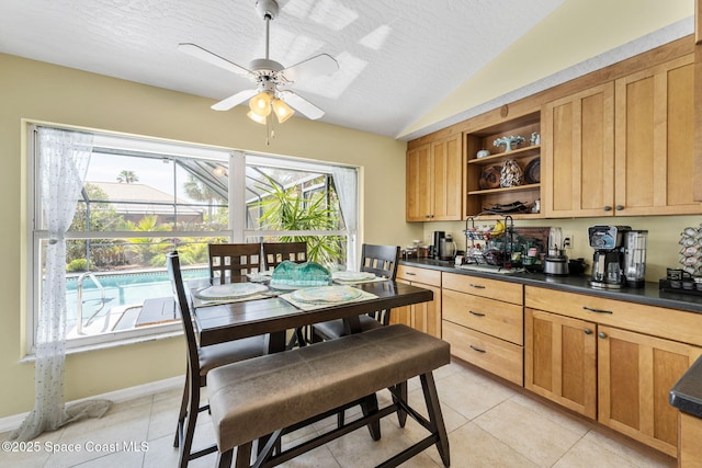 kitchen with a ceiling fan, open shelves, vaulted ceiling, a textured ceiling, and dark countertops