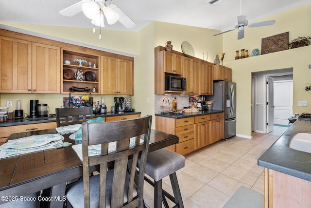 kitchen featuring dark countertops, light tile patterned floors, stainless steel appliances, and ceiling fan