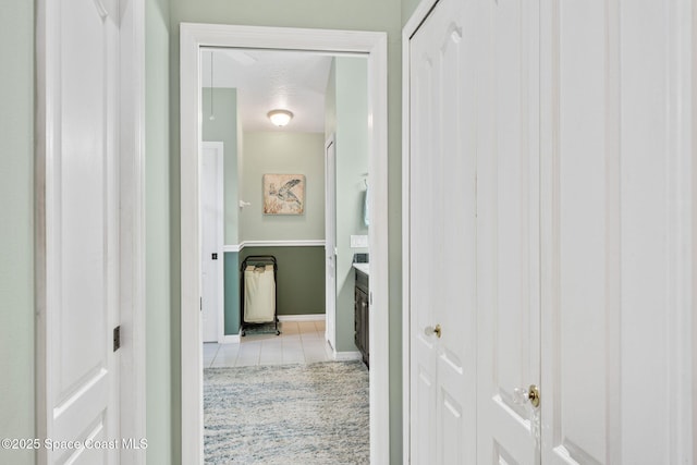 hall featuring tile patterned flooring and baseboards