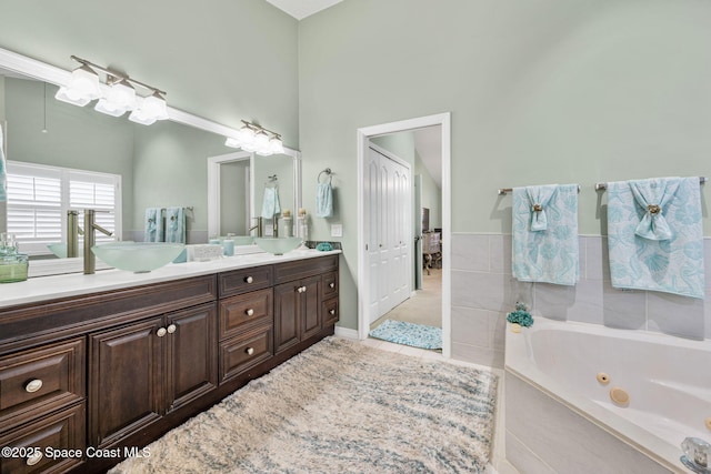 full bathroom featuring tile patterned flooring, double vanity, a jetted tub, and a sink