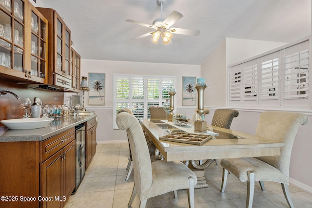 dining space with a textured ceiling, light tile patterned flooring, baseboards, and ceiling fan