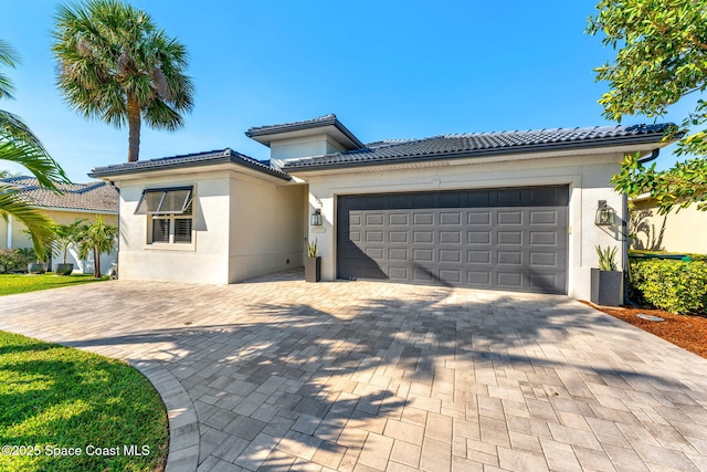 view of front of home featuring a garage, decorative driveway, stucco siding, and a tile roof