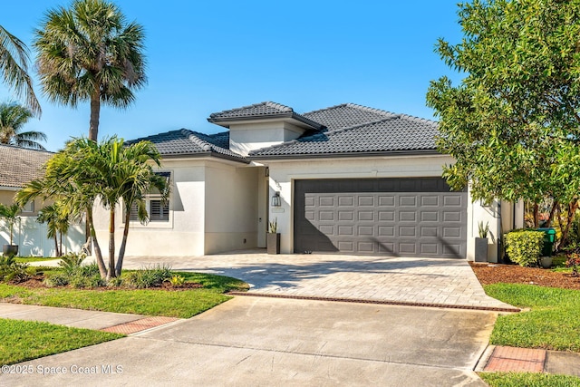 view of front of home with stucco siding, an attached garage, a tile roof, and driveway