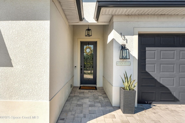 doorway to property featuring a garage and stucco siding