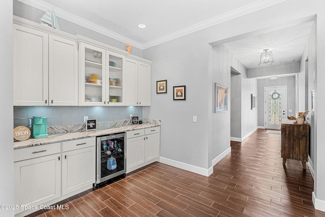 bar with wood finish floors, a notable chandelier, beverage cooler, backsplash, and baseboards