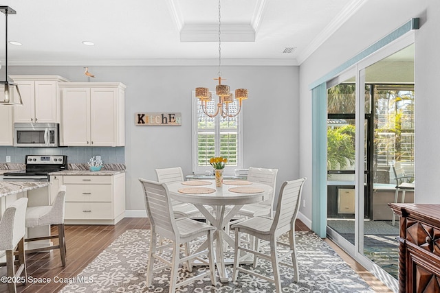 dining space with baseboards, a tray ceiling, ornamental molding, light wood-style flooring, and a notable chandelier