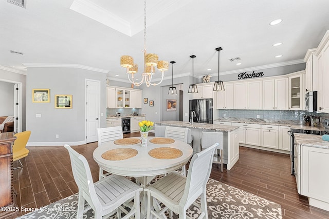 dining space featuring beverage cooler, a notable chandelier, visible vents, and wood tiled floor