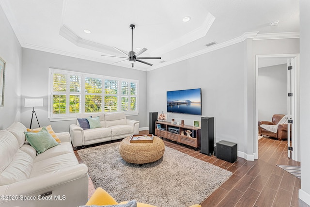 living room featuring baseboards, wood tiled floor, ornamental molding, a raised ceiling, and a ceiling fan