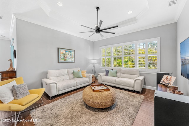 living area with visible vents, crown molding, a ceiling fan, and wood finished floors