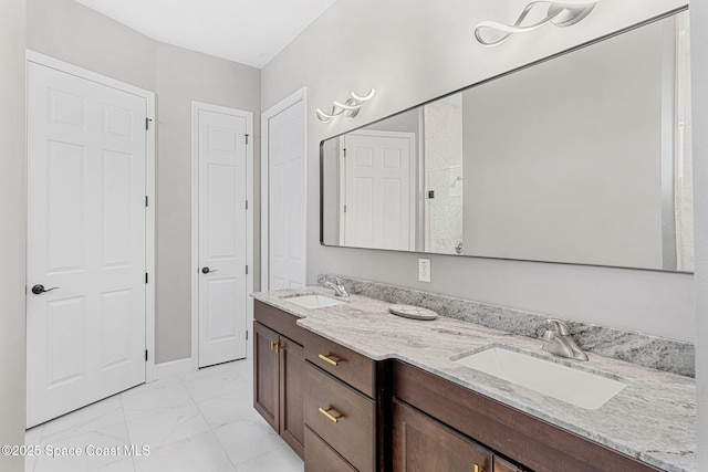 bathroom featuring double vanity, marble finish floor, and a sink