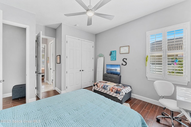 bedroom with a closet, baseboards, a ceiling fan, and wood tiled floor