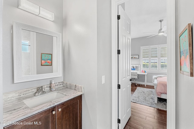 ensuite bathroom featuring vanity, wood finished floors, a ceiling fan, baseboards, and connected bathroom